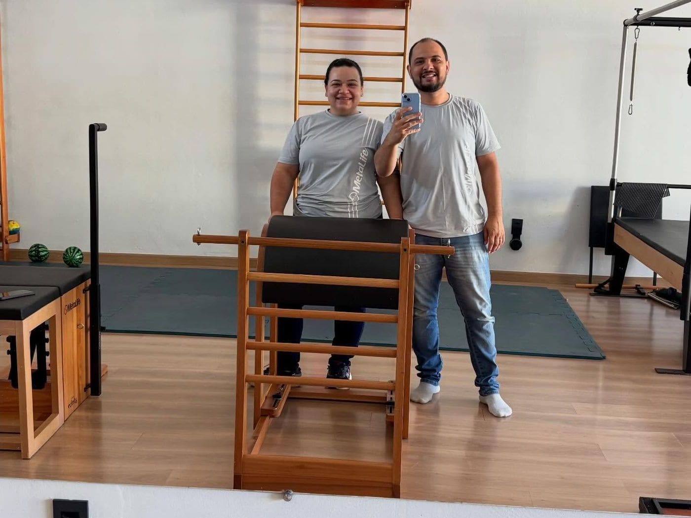 William e Ariane num estúdio de pilates, ao lado de um equipamento que montaram