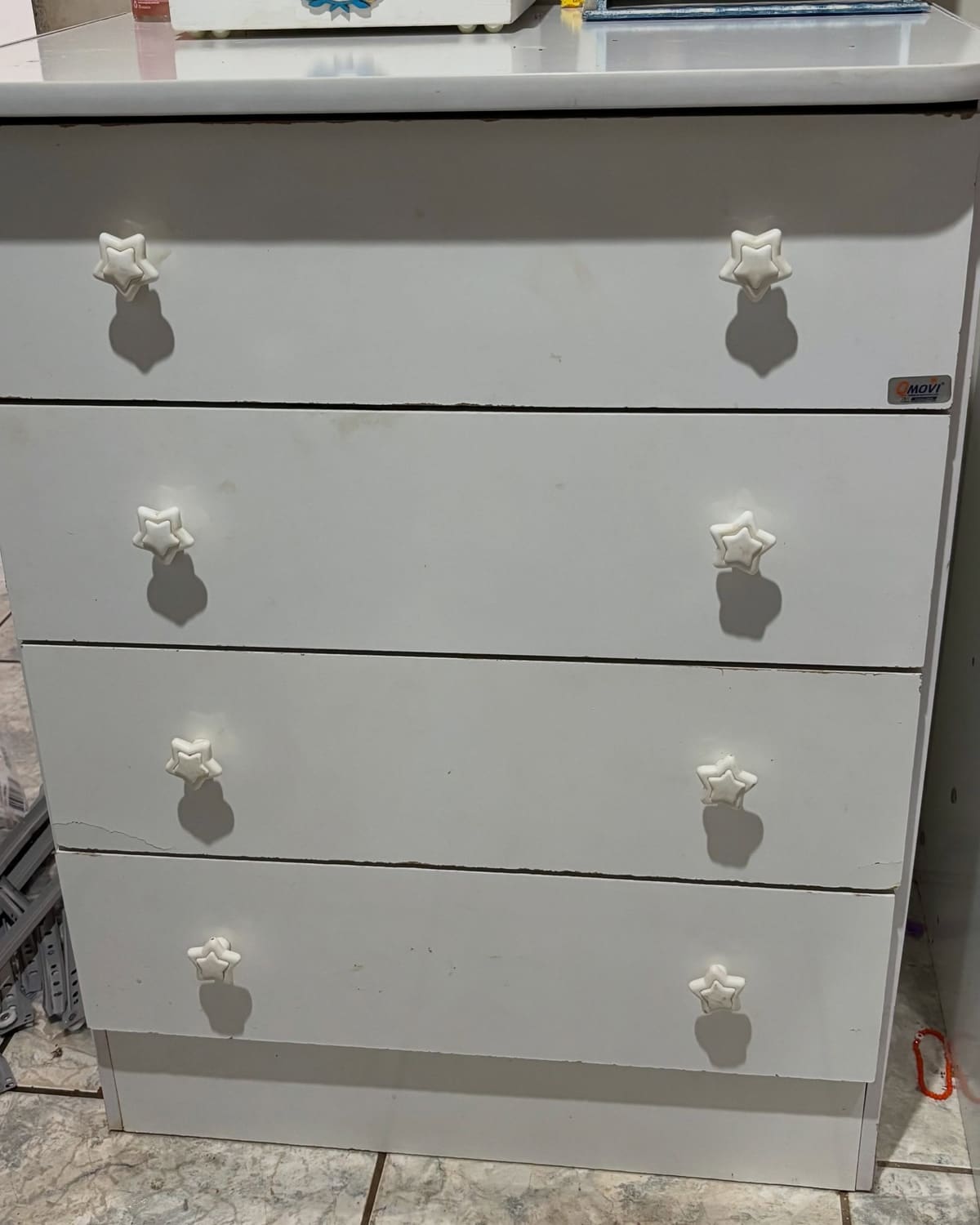 A mesma cômoda com as quatro gavetas fechadas, alinhadas entre si e no lugar, cada frente rente à outra.